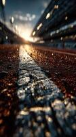 Sunset over a racetrack with illuminated stadium stands and wet asphalt in the foreground photo
