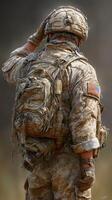 Soldier saluting in military uniform during a dusty environment at sunset photo