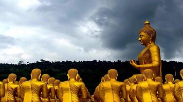 a large group of golden buddhas are standing in front of a cloudy sky video