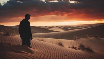 Person Standing on Sand Dune at Dramatic Sunset in Desert Landscape photo