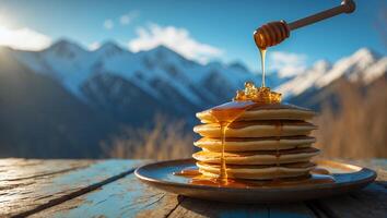 Stack of Pancakes Being Drizzled with Honey Against a Mountain Backdrop photo