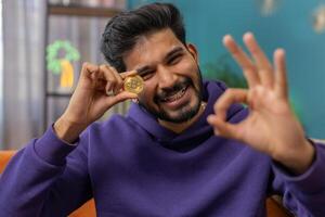 Indian man stock trader earning bitcoins, online monitoring trading operations mining hold BTC coins photo