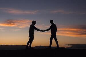 Two figures shake hands at sunset photo