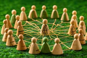 Wooden figures connected by a web on green grass photo