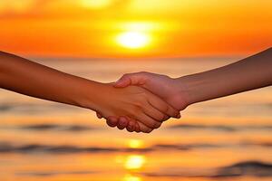 Two people holding hands over the ocean at sunset photo
