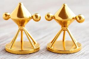 Two gold-plated miniature atomic models on a light wooden surface photo
