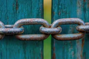 Rusty chain links on teal wooden fence photo