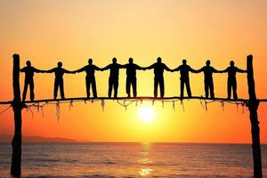 Unity at sunset. Silhouettes of people holding hands across a rustic bridge at sunrise photo
