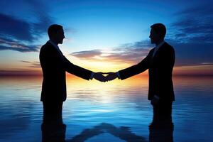 Two businessmen shaking hands over water at sunset photo