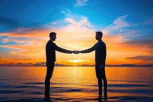 Two men shaking hands at sunrise over water photo