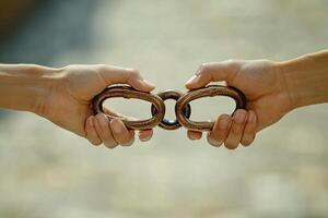 Two hands holding a chain link, connection photo