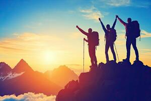 Three people with backpacks on top of a mountain at sunset photo