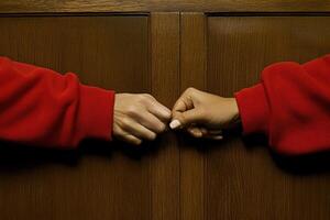 Two hands clasped in solidarity, adorned in vibrant red photo