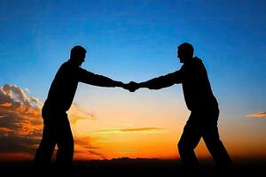 Two men in silhouette, hands clasped at sunset photo