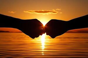 Two fists meet at sunset over water photo