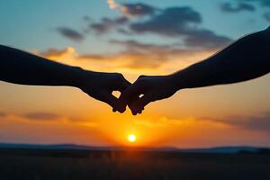 Silhouetted hands clasped at sunset photo