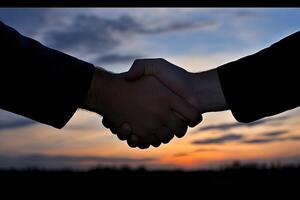 A handshake at sunset. Two people shaking hands against a beautiful sunset backdrop photo