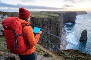 Adventurer using tablet on clifftop photo