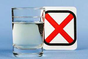 Clear glass of water beside a no symbol photo