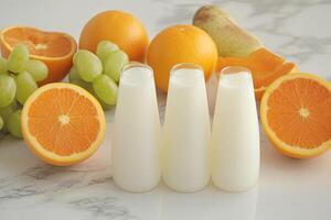 Fresh yogurt drinks surrounded by citrus fruits and grapes photo