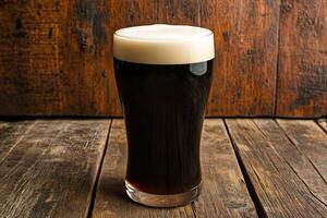 Dark beer in a glass on a wooden table photo