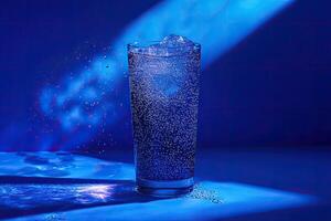Sparkling water in a glass, illuminated by vibrant blue light. Ice cubes and bubbles are prominent photo