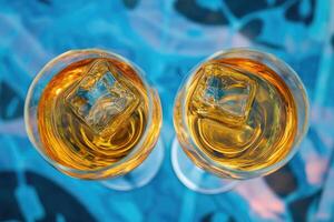 Two glasses of amber liquid with ice cubes photo