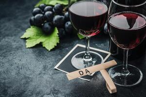 Two glasses of red wine, a bunch of grapes, and a tasting note photo
