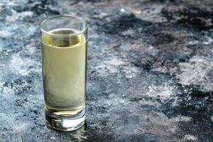 Clear liquid in a shot glass on a dark surface photo