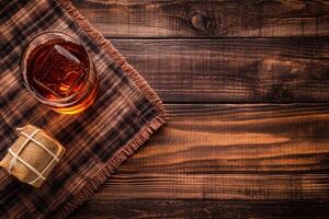 A glass of amber liquor with ice cubes on a rustic wooden surface photo