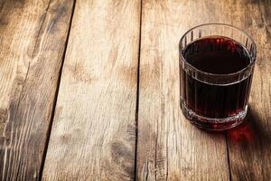 Dark drink in glass on wooden table photo