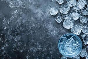 Ice cubes scattered on dark surface with glass bowl photo