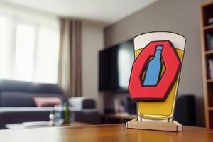 A stylized beer glass and bottle graphic on a wooden stand, in a living room photo