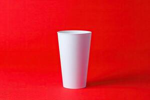 Plain white tall cup on red background photo