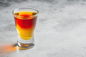 Shot glass of amber colored spirit photo