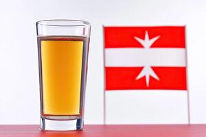 Shot glass of amber liquid, flag in background photo