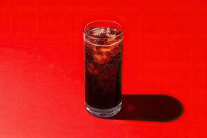 Sparkling dark drink in a glass with ice photo