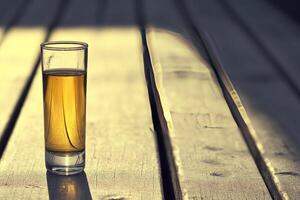Small glass of amber liquid on weathered wood photo