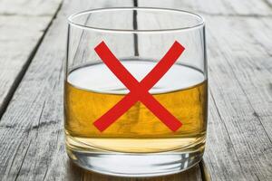 A glass of whiskey with a red cross on it photo