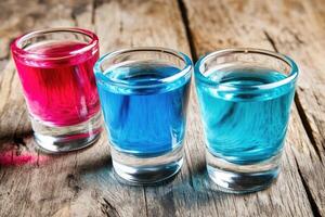 Colorful shot glasses of colorful drinks on a rustic wooden table photo