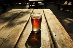 Amber beer in a glass on a wooden picnic table photo