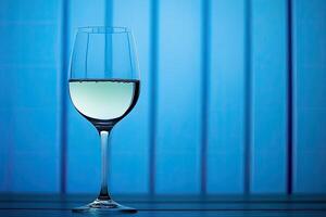 A glass of white wine against a blue background photo
