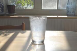 Glass of water on a table, sunlight photo