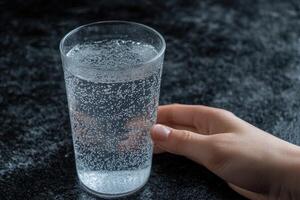 Sparkling water in a glass, held by a hand photo