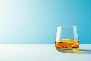 Single glass of amber liquid on a light surface photo