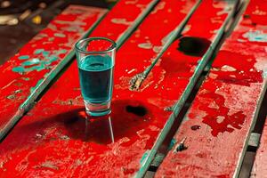 Teal shot glass on weathered red wooden planks photo