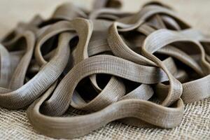 Dark brown pasta strands, a close-up view of a pile of uncooked noodles, with a slightly rough texture photo