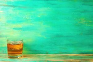 A glass of amber liquid with ice on a teal background photo