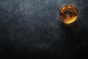 Glass of amber liquid on dark stone photo