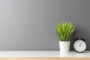 Minimalist workspace setup with a potted plant and alarm clock photo
